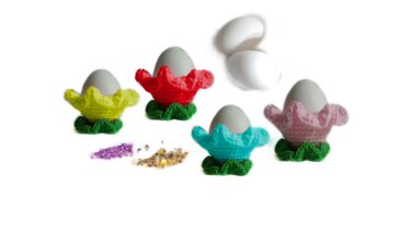 Gehäkelte bunte Eierbecher in Blumenform mit grünem Blattfuß und Eiern