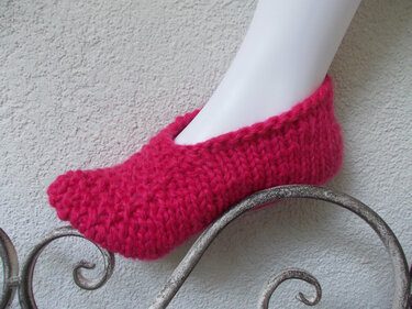 Seitliche Ansicht eines fuchsiafarbenen, schlicht gestrickten Hausschuhs auf einem Mannequinfuß