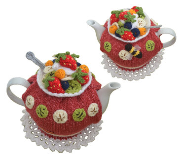 Two red knitted teapot cozies with fruit and bee appliques on white teapots.