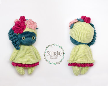 Front- und Rückansicht einer gehäkelten Amigurumi-Puppe mit Locken, Blumenapplikationen und Rüschenrock