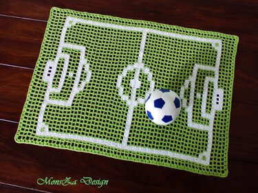 Rechteckiges gehäkeltes Deckchen in Grün mit weißen Markierungen eines Fußballfeldes und einem blau-weißen Ball