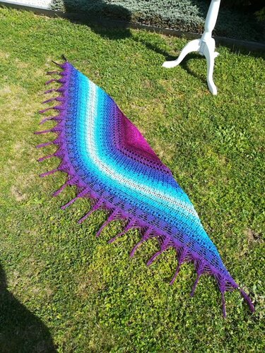 Halbrundes gehäkeltes Tuch in Violett-, Türkis- und Blautönen mit Fransen auf Gras