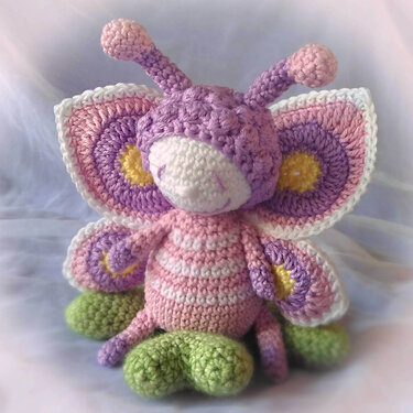 Amigurumi Schmetterling gehäkelt sitzt auf grünen Blättern