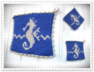 Drei blaue gehäkelte Topflappen mit beigem Seepferdchen- und Wellenmuster, ein größeres und zwei kleinere, auf hellem Untergrund.