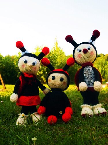 Drei gehäkelte Marienkäfer-Amigurumi in Rot und Schwarz auf Gras