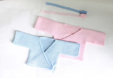 Two pastel crochet baby wrap cardigans in pink and blue laid flat with coordinating ties