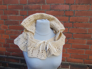 Gehäkelter Damen-Bolero in Beige mit Rüschenkragen auf Schaufensterpuppe