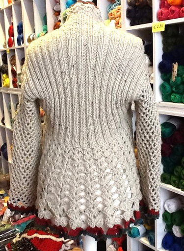 Cremefarbene Strickjacke von hinten mit vertikal geripptem Rückenteil, offenem Lochmuster am Saum und netzartigen Ärmeln