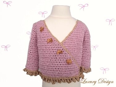 Rosa gehäkelte Wickeljacke für Baby und Kleinkind mit beigen Rüschen und kleinen Schleifen auf einer Schaufensterpuppe.