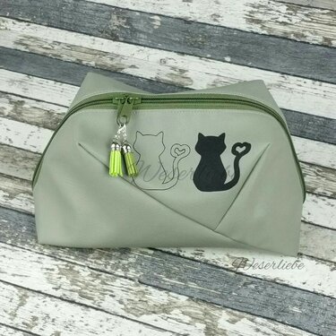 Kosmetiktasche mit zwei unterschiedlichen Katzenplots (eine Kontur, eine schwarze Fläche) und grünen Quasten am Reißverschluss