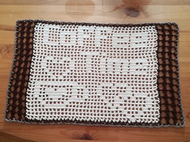 Rechteckiges, gehäkeltes Deckchen mit HOME-Schriftzug, weiß mit dunkelbraunem Rand
