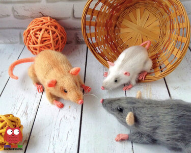 Three small crocheted amigurumi rats in different colors shown with a wicker basket and decorative balls