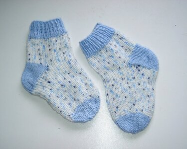 Paar weißer Babysocken mit blauen Sprenkeln und hellblauem Bündchen