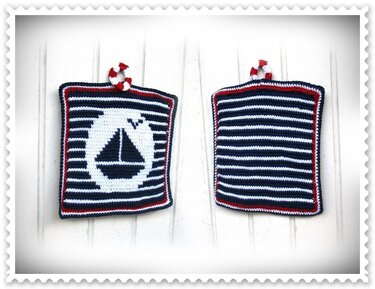Zwei gehäkelte Topflappen in Dunkelblau, Weiß und Rot; vorn Segelboot-Motiv im weißen Kreis, hinten gestreifte Rückseite, mit gedrehter Aufhängeschlaufe
