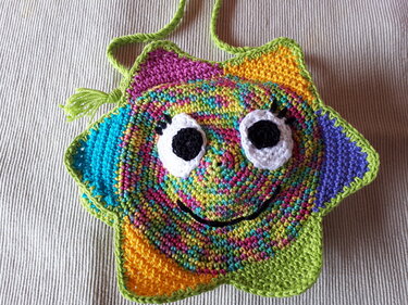 sternförmige gehäkelte Umhängetasche in bunten Farben mit aufgenähten Augen und grüner Einfassung