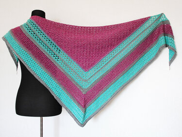 Gehäkeltes Dreieckstuch in Magenta, Türkis und Grau auf einer Schneiderpuppe drapiert, mit offenem Spitzenmuster.
