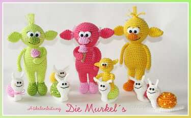 Verschiedene gehäkelte Amigurumi-Figuren: drei größere Fabelwesen (grün, pink, gelb) und mehrere kleine, bunte Schnecken.