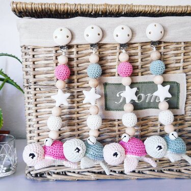 Vier gehäkelte Schnullerketten mit Schildkröten, Holzperlen, Sternen und Clips an einem geflochtenen Korb