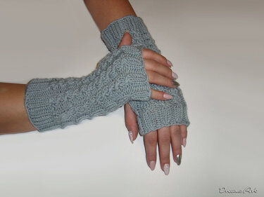 Hellgraue gestrickte, fingerlose Armstulpen mit Zopfmuster an Händen.