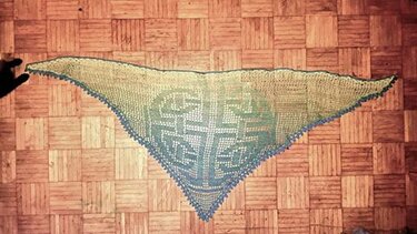 Gehäkeltes Dreieckstuch in Gelbgrün und Türkisblau mit keltischem Knotenmuster auf Parkett