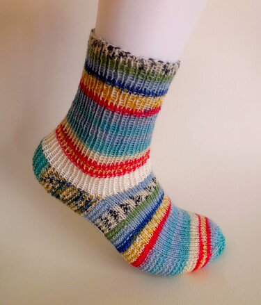 Bunte gestrickte Socke mit horizontalen Streifen auf weißem Fußmodell vor hellem Hintergrund.