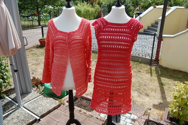 Korallenrotes gehäkeltes Set aus Cardigan mit langen Ärmeln und ärmellosem Kleid auf Schaufensterpuppen.