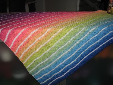 Gestricktes Dreieckstuch mit Regenbogen-Farbverlauf und schmalen weißen Streifen, flach liegend