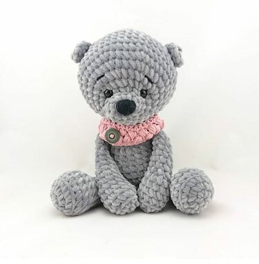 Gehäkelter grauer Amigurumi-Teddybär sitzend mit rosa Halskrause und Knopf