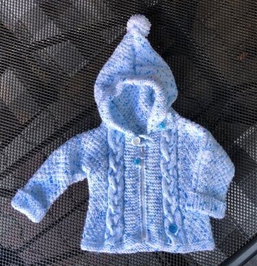 Gestrickte Babyjacke blau-weiß mit Kapuze und Pompon, flach liegend
