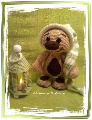 Gehäkelter Amigurumi-Teddybär mit gestreifter Schlafmütze neben gehäkelter Laterne
