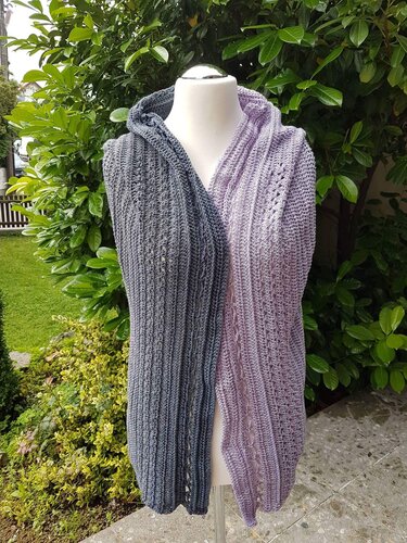 Mannequin wearing long hooded sleeveless crochet vest with grey and lavender panels, ribbed texture