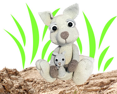Gehäkeltes hellgraues Känguru mit Baby im Beutel auf felsigem Untergrund.