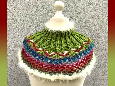 Kurzponcho mit grünem Rippkragen, mehrfarbigen Häkelreihen und weißem Flauschsaum