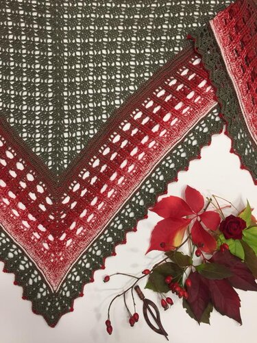 Red and olive green crocheted triangle shawl with lace pattern and scalloped edge, styled with autumn foliage.