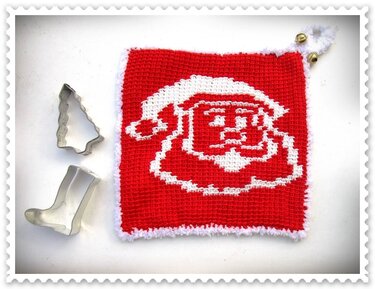 Roter gehäkelter Topflappen mit weißem Weihnachtsmannkopf, flauschigem Rand und zwei goldenen Glöckchen; daneben Ausstechformen Tannenbaum und Stiefel.