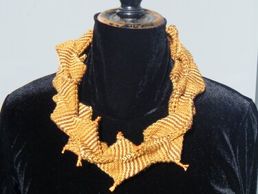 Gestrickter Halskragen in Gelb und Braun mit Zickzackmuster auf schwarzer Schaufensterpuppe