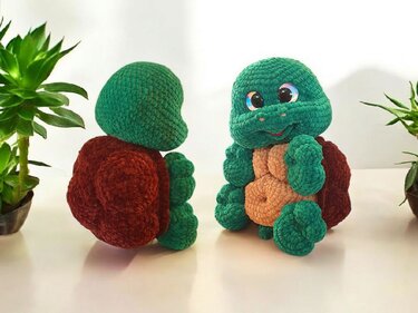 Two crocheted amigurumi turtles with green bodies, tan bellies and dark brown shells; one faces forward, the other shows its back shell.
