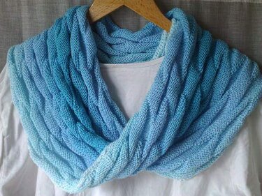 Gestrickter blauer Loop-Schal mit Farbverlauf auf Holzhänger über weißem Shirt