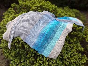 gehäkeltes dreieckstuch blau beige verlauf auf grünem grund