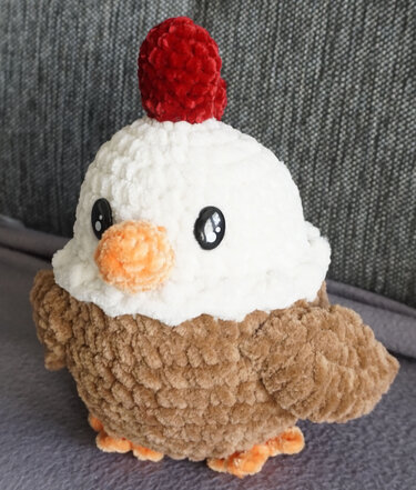 Kuscheliges gehäkeltes Amigurumi-Huhn mit weißem Kopf und rotem Kamm