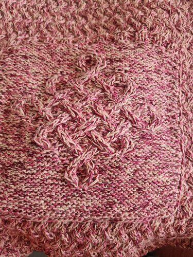 Detail eines rosa-melierten Schals mit geflochtenem Zopfmuster und gezackter Borte