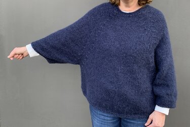 Detailansicht eines dunkelblauen gestrickten Oversize-Pullovers mit Raglannähten und lockerem Fall.