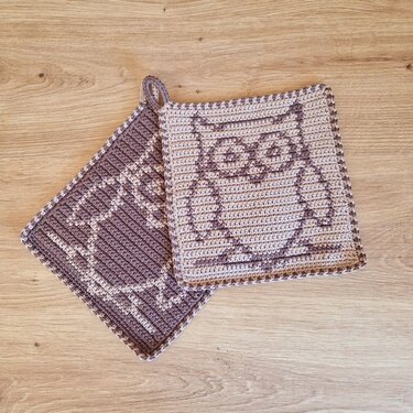 Zwei gehäkelte Topflappen mit Eulenmotiv in Braun und Beige auf Holz