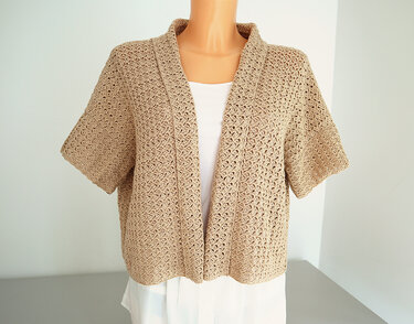 Beige crocheted short-sleeve open-front jacket on mannequin