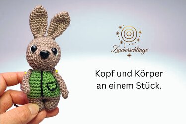 Nahaufnahme eines braunen Amigurumi-Hasen mit grüner Weste, in einer Hand gehalten
