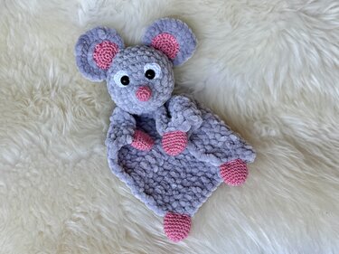 Grey plush crochet mouse lovey with pink ears, nose and corner paws on white faux-fur background