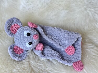 Grey crochet mouse snuggle blanket with pink crochet ears, pink nose and pink corner accents on a cream faux-fur background