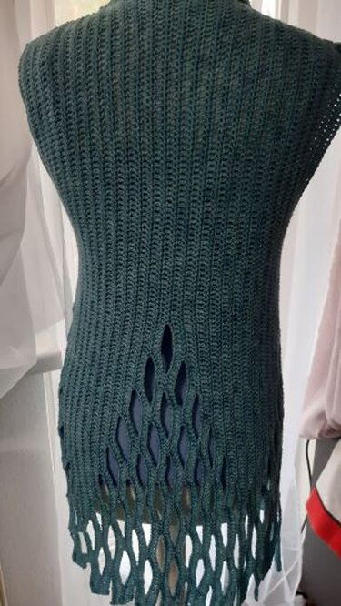 Rückansicht einer dunkelgrünen gehäkelten Weste mit offenem Rautenmuster am unteren Rücken auf einer Schneiderpuppe.