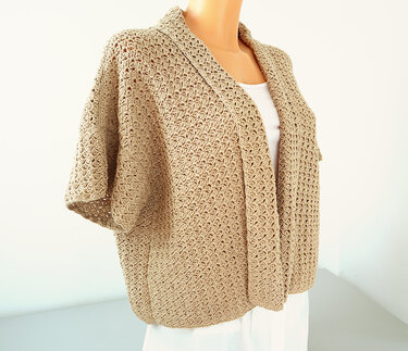 Beige crocheted open-front jacket with shawl collar on a mannequin