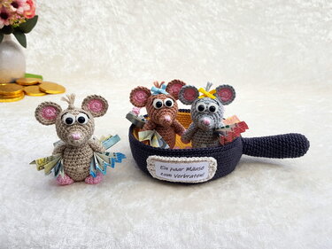 Drei gehäkelte Amigurumi‑Mäuse, zwei in einer gehäkelten Pfanne, dekoriert mit gefalteten Euroscheinen; Pfannenschild: Ein paar Mäuse zum Verbraten!